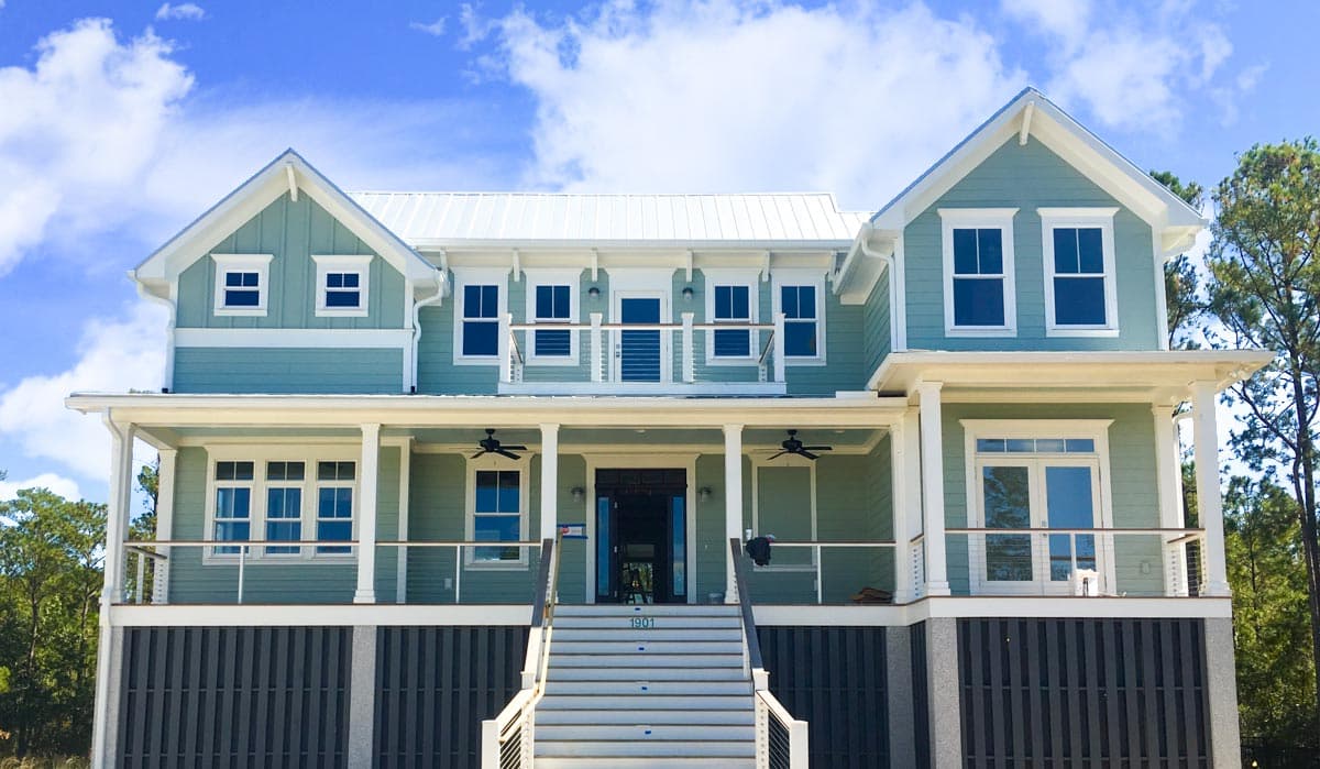 House plan exterior: Coastal style, two-story home with a wraparound porch, multiple gables, and metal roof.
