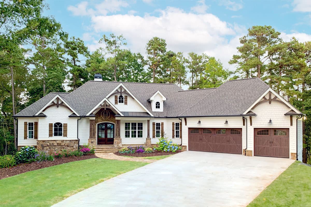 House plan exterior: One-story Craftsman home with a gabled roof, dormers, and a covered front porch, featuring a two-car garage.