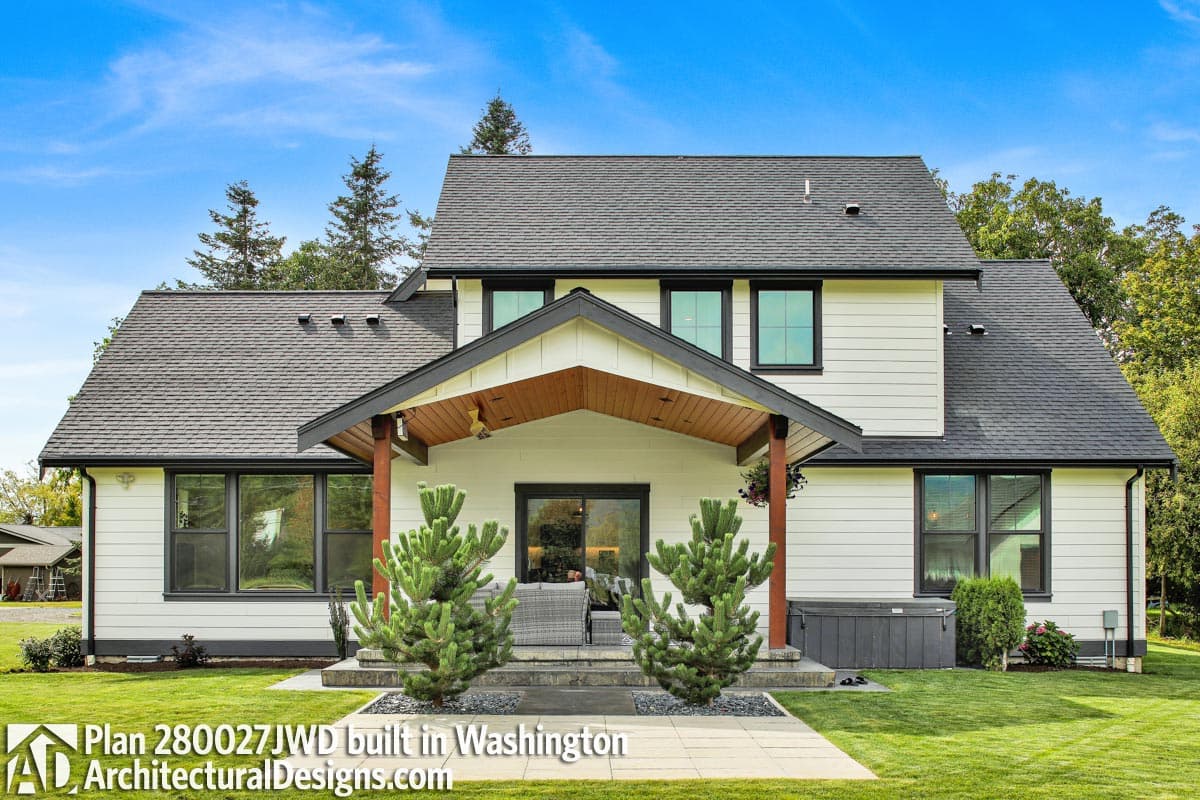 House plan exterior: Modern Farmhouse style, two stories, prominent gabled entrance with wooden beams, white siding, dark-trimmed windows.