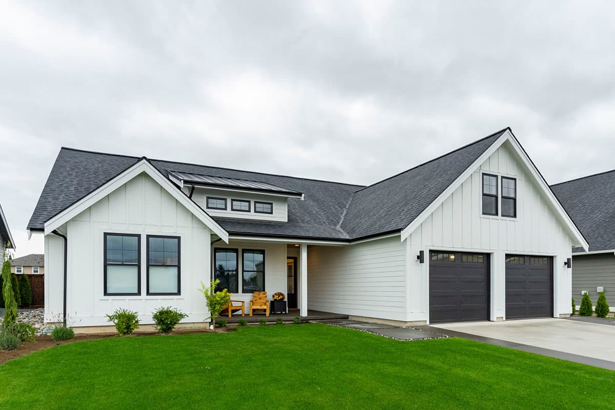 Modern Farmhouse house plan exterior with white board and batten siding, metal roof accents, dormer, and a three-car garage.