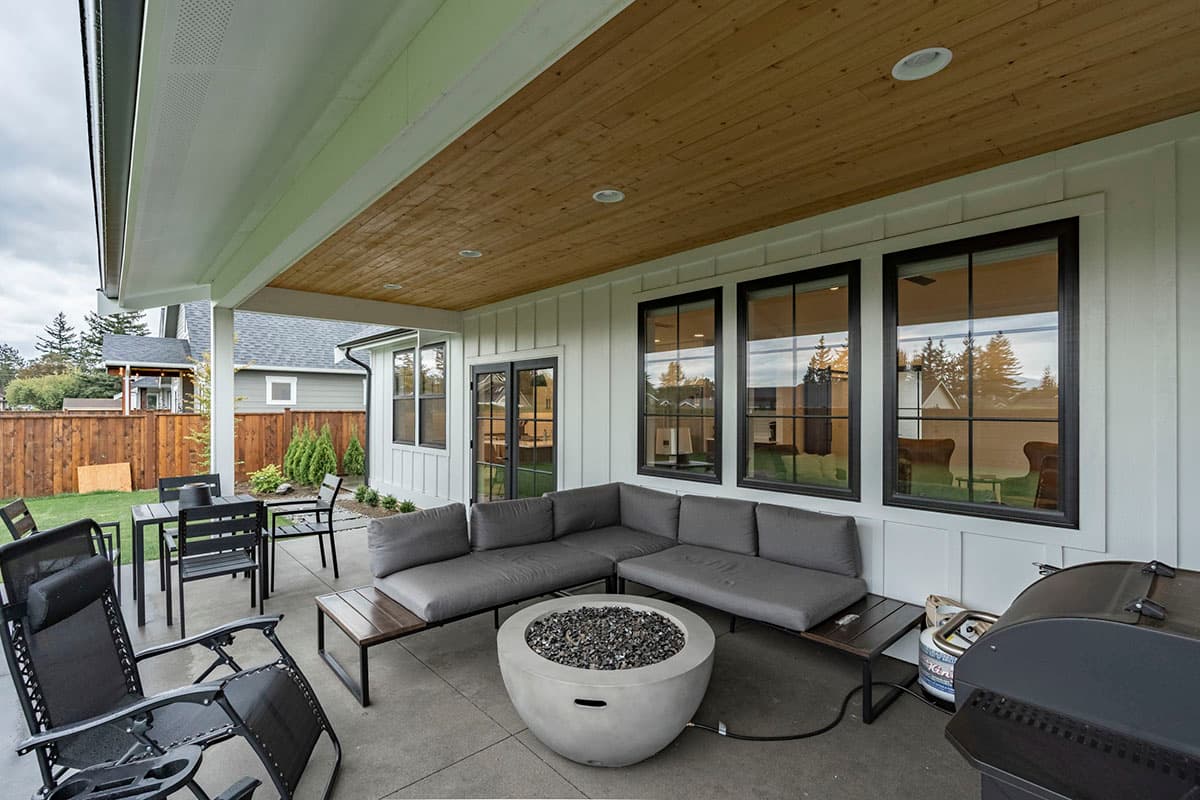 Covered patio with seating, dining table, fire pit, and grill.