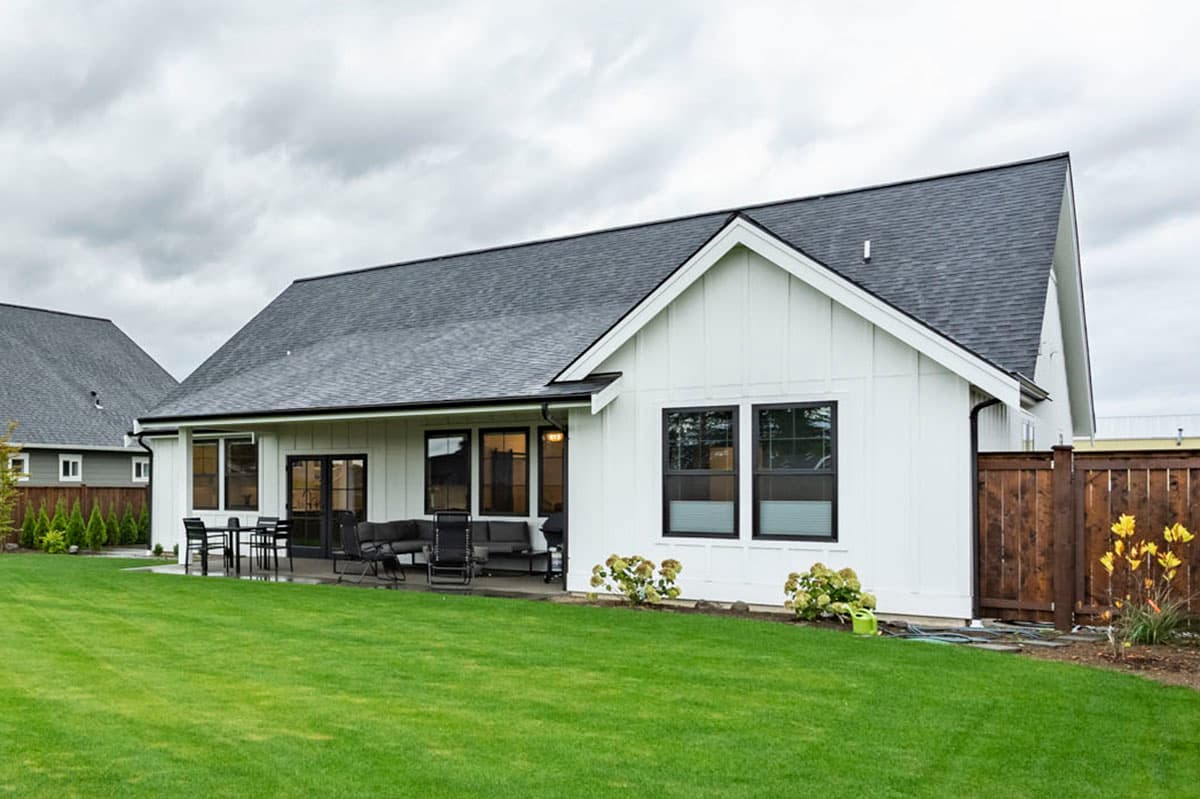 Modern Farmhouse house plan exterior with white board-and-batten siding, gable roof, and covered patio with outdoor seating.