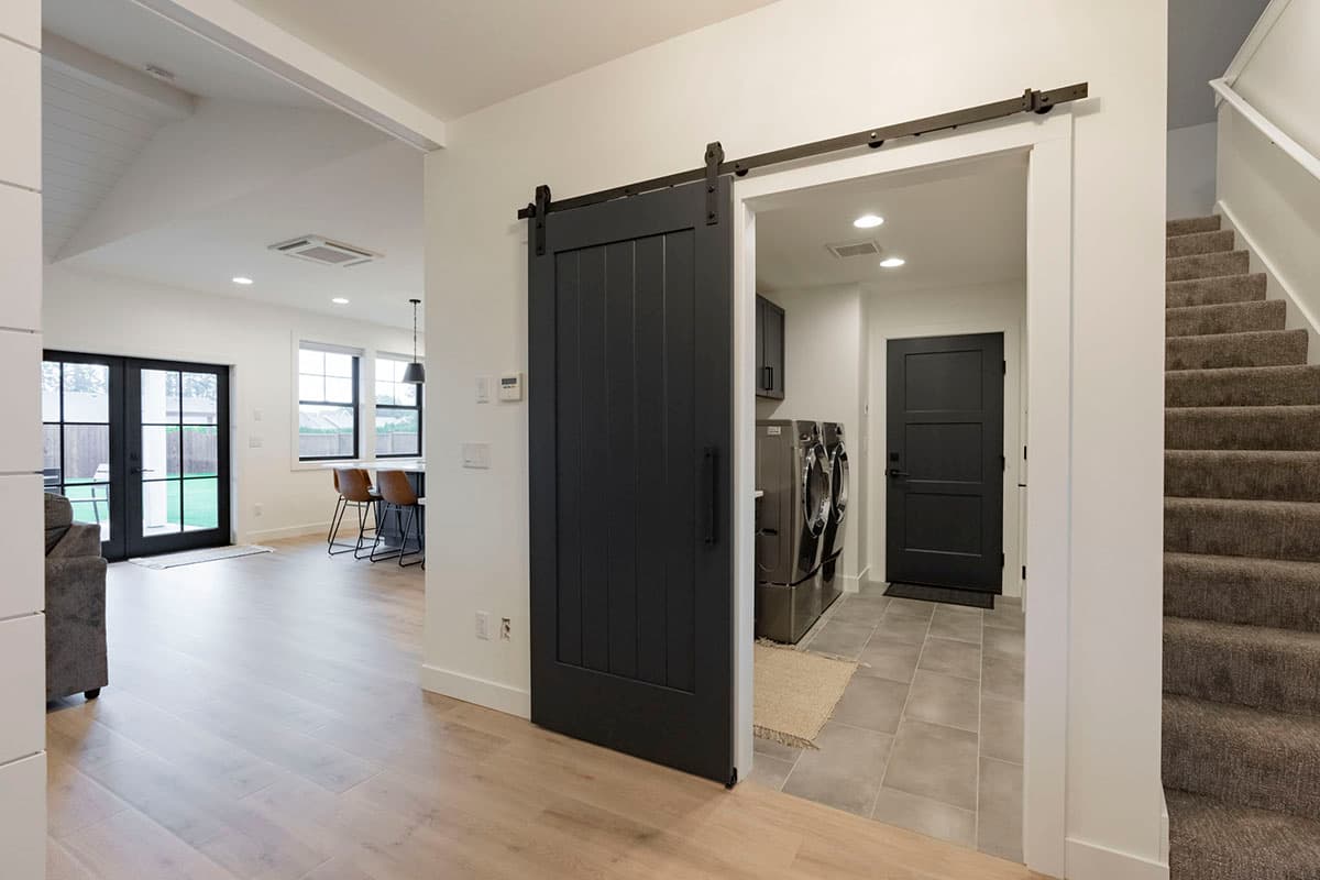 Interior view showing a laundry room with washer/dryer, a barn door, and a staircase.