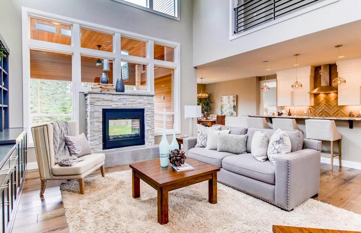Great room with vaulted ceiling, stone fireplace, and open kitchen with island. A balcony overlooks the space.
