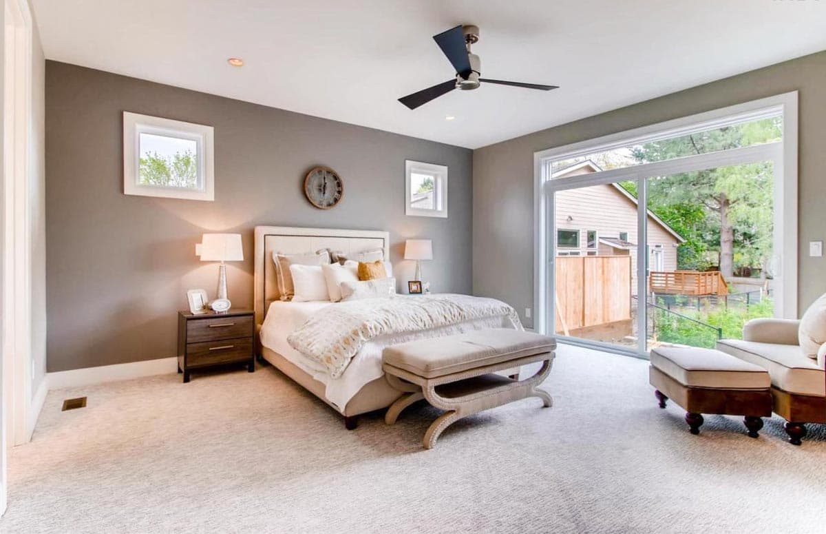 Primary bedroom with king bed, nightstand, ceiling fan, and sliding glass door to deck. Modern style.