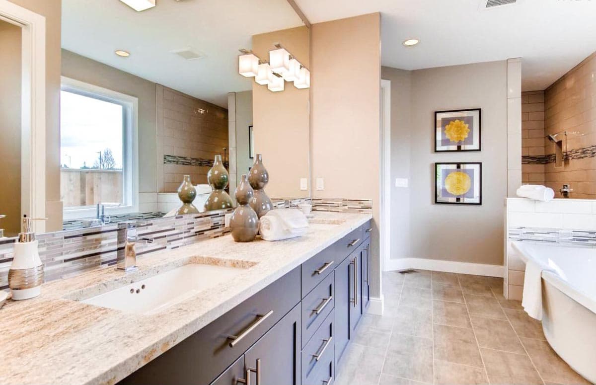Bathroom with double vanity, granite countertops, tile accents, window, and soaking tub with tile shower.