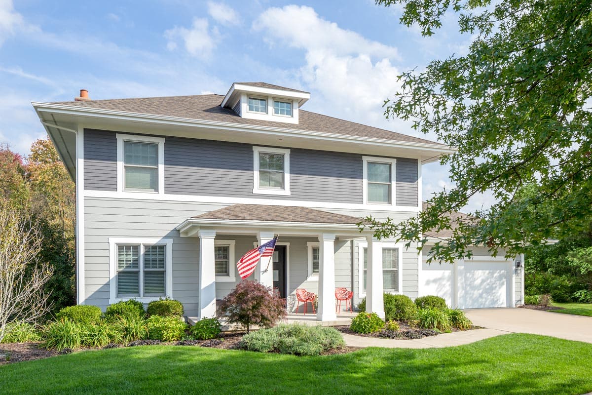 Two-story house plan exterior with Craftsman style. Features include a front porch supported by columns, gabled roof, and a dormer window.