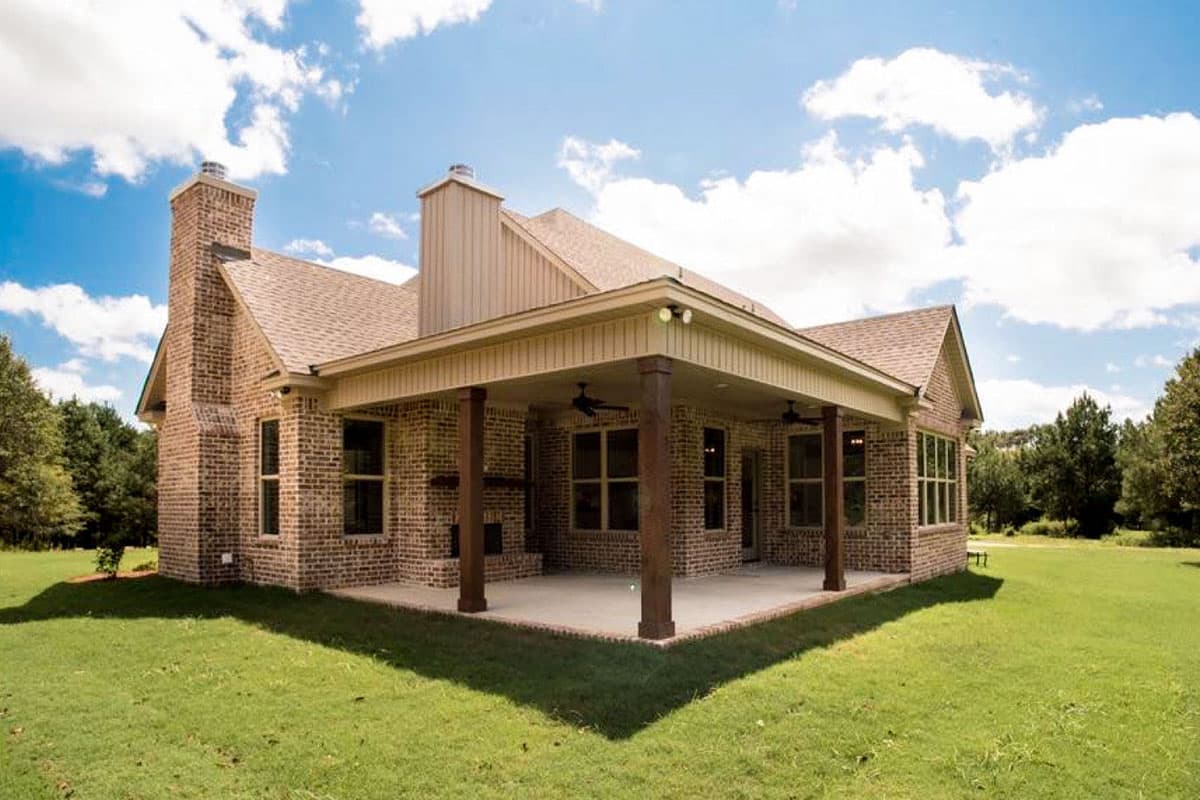 House plan exterior: Brick ranch with covered porch, two chimneys, and large windows.