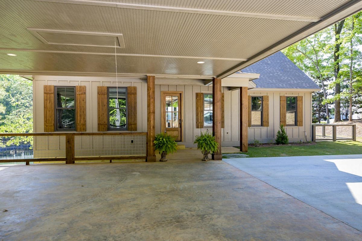House plan exterior with covered carport, wood posts, board-and-batten siding, and wooden shutters.