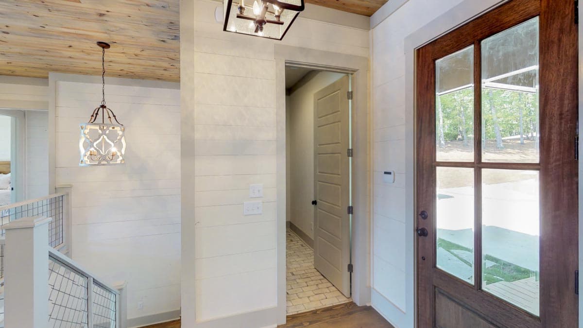 Interior entryway with wood-paneled ceiling, shiplap walls, a glass-paneled front door, and a decorative lantern.