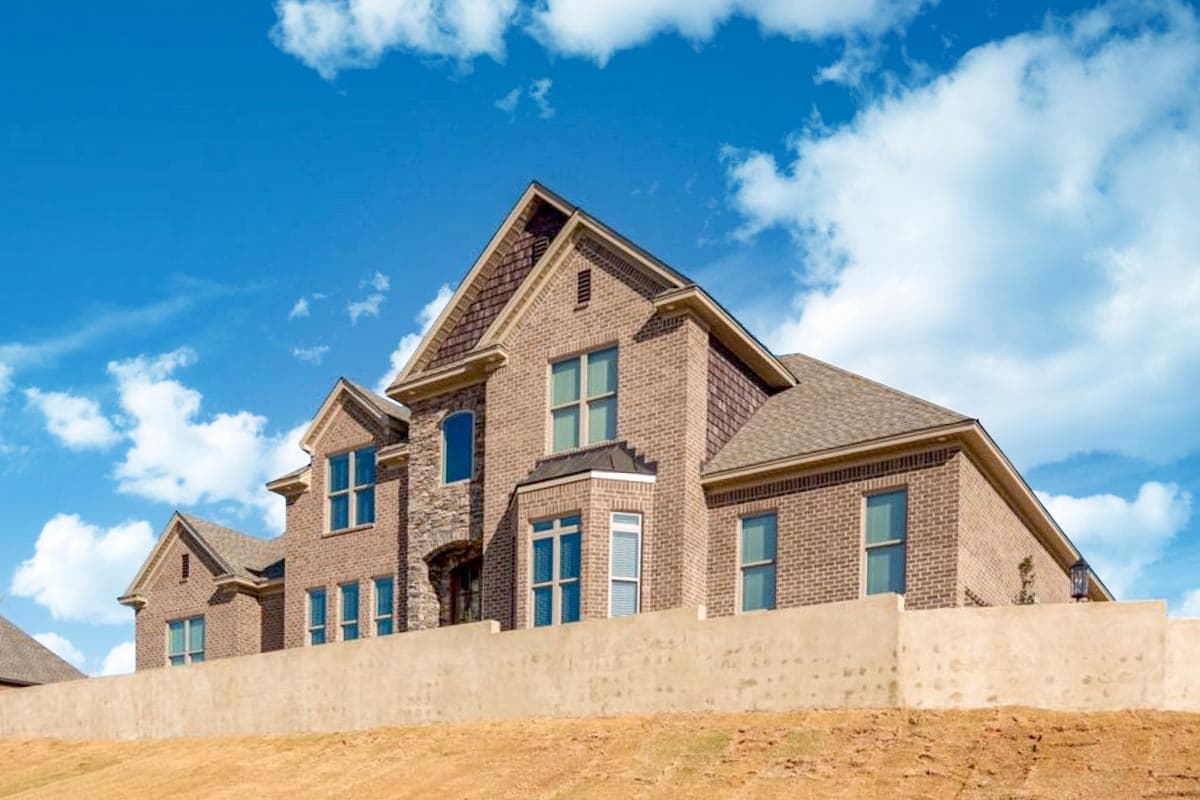 House plan exterior shows a two-story brick home with multiple gables, stone accents, and bay windows.