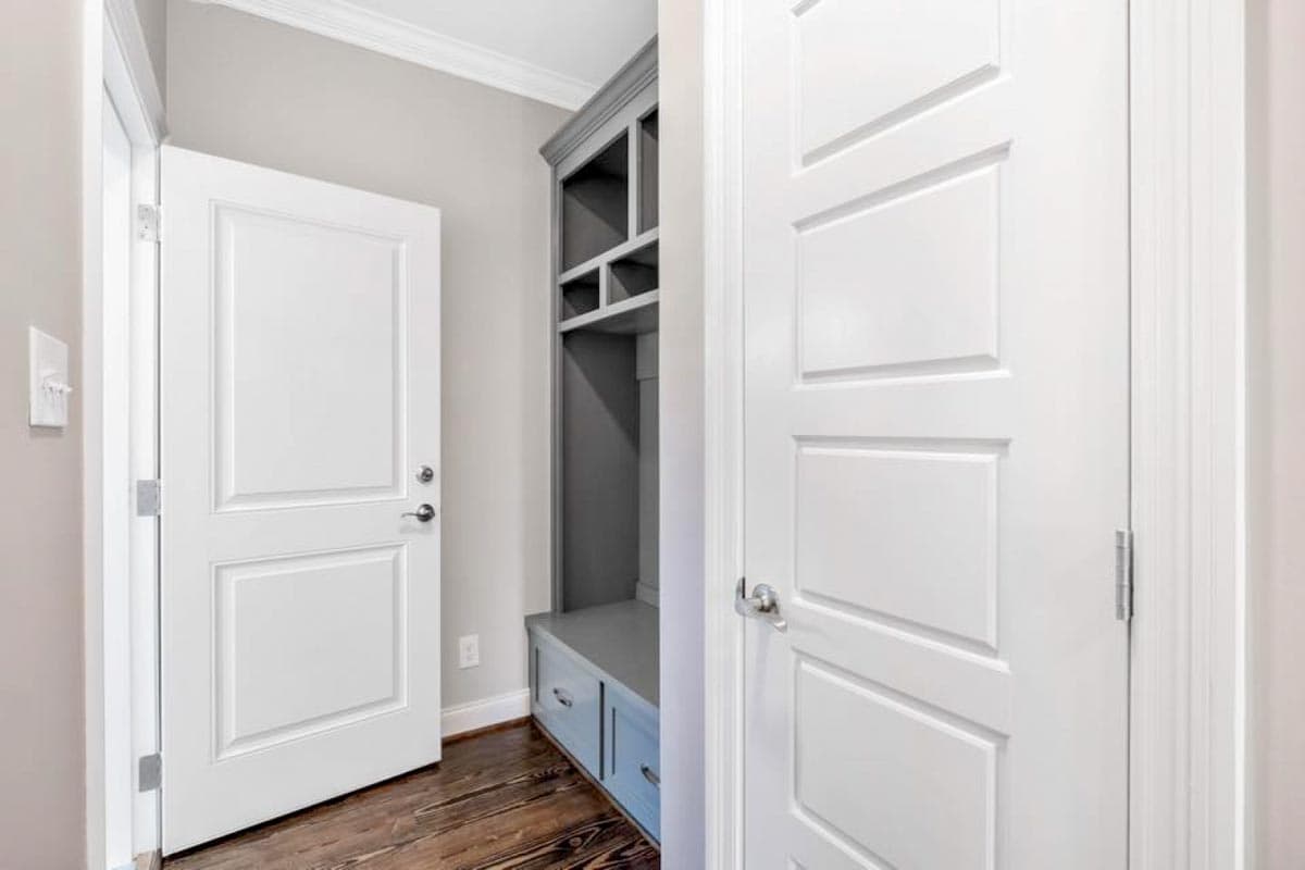 Interior view of a mudroom with a built-in bench, cubbies, and white doors.