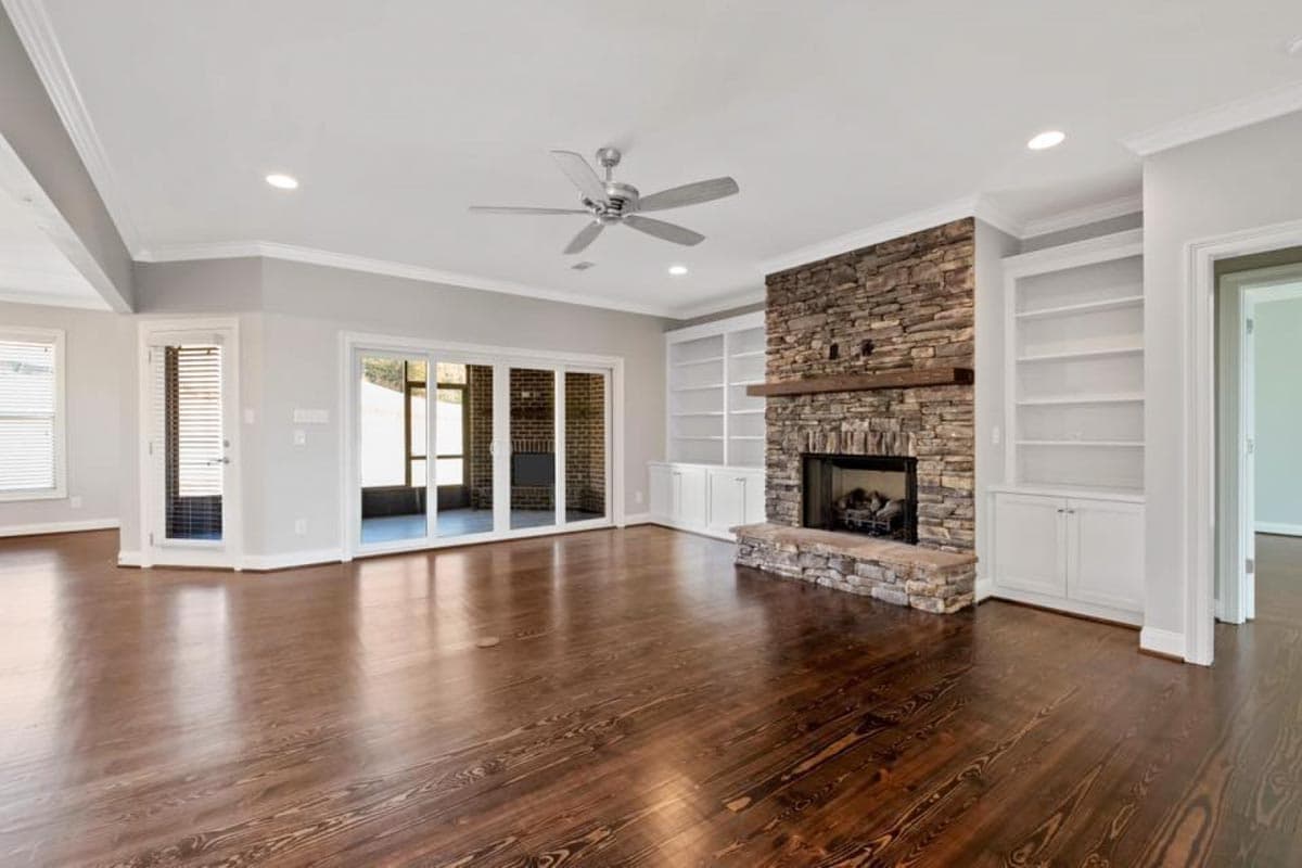 Living room with stone fireplace, built-in bookshelves, and large sliding glass doors to a screened porch.