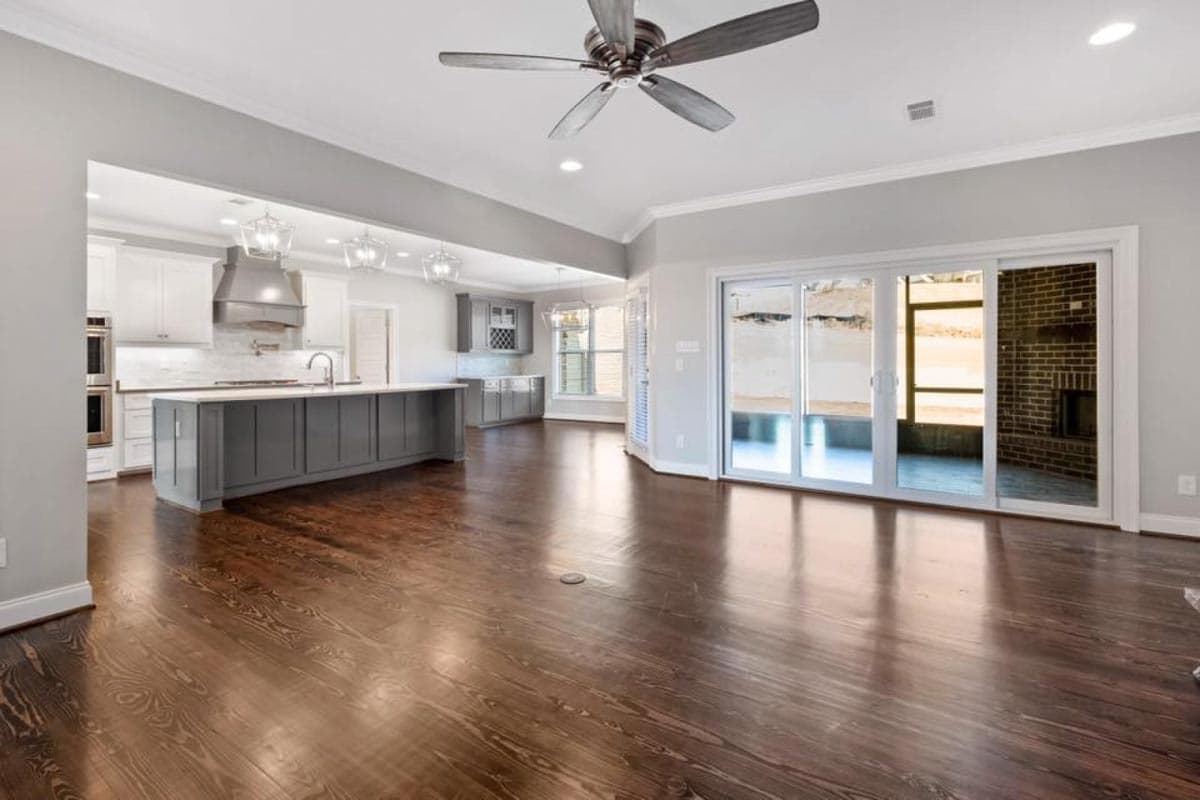 Open concept living area with kitchen island, vaulted ceiling, and sliding glass doors leading to an outdoor fireplace.