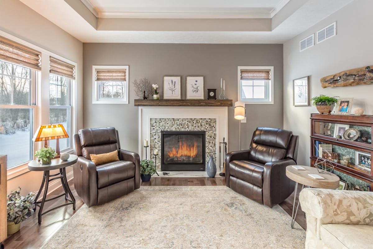 Living room interior with fireplace, two recliners, large windows, and coffered ceiling.