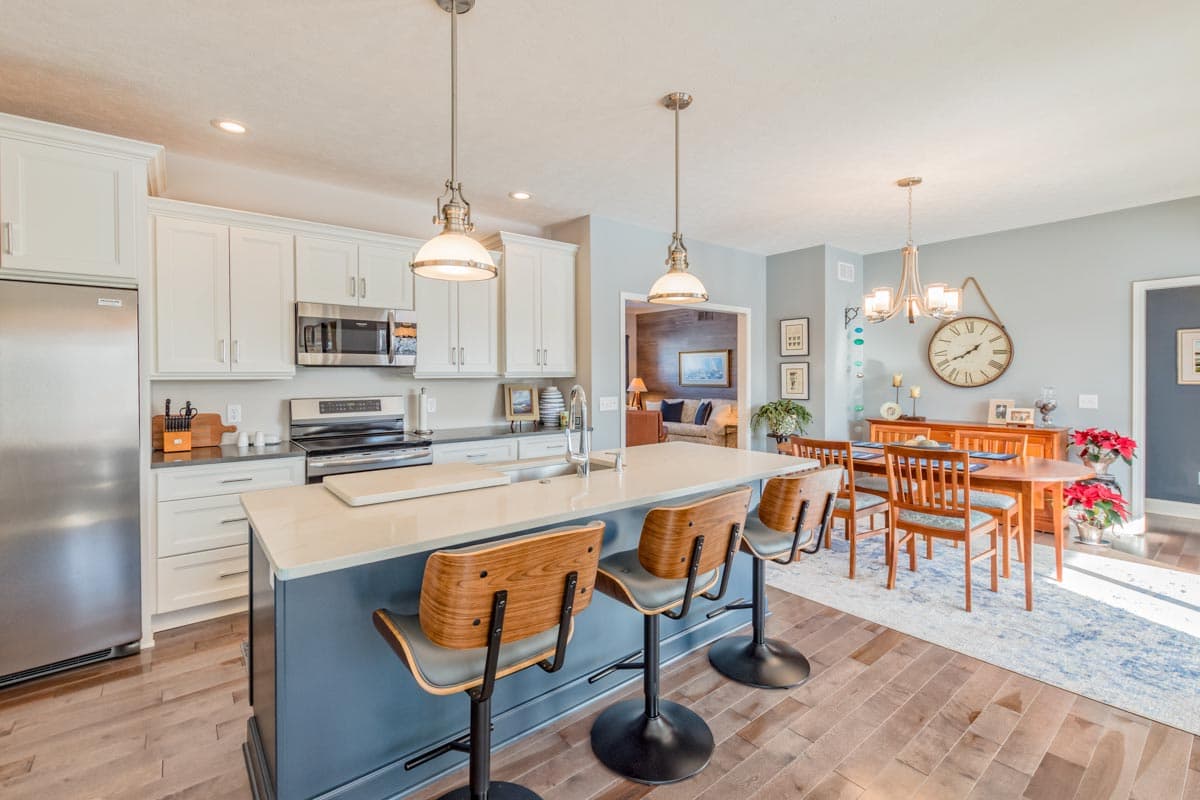 Modern kitchen with white cabinets, island with seating, and adjacent dining area with wooden table and chairs.
