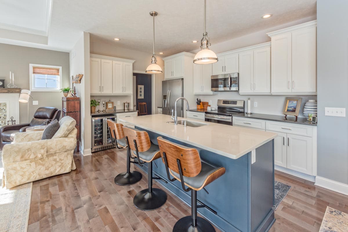 Contemporary kitchen with island seating, white cabinetry, stainless steel appliances, and hardwood flooring.