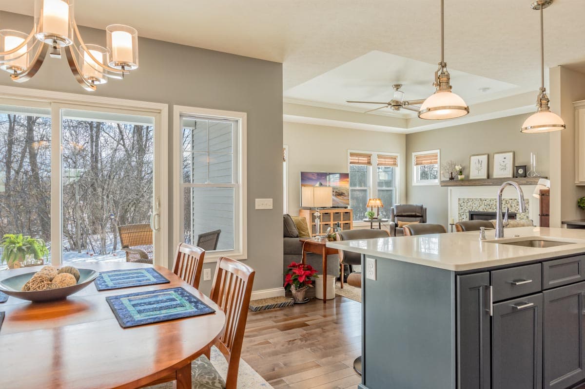 Kitchen island with sink, open dining area, and great room with fireplace and media center visible.
