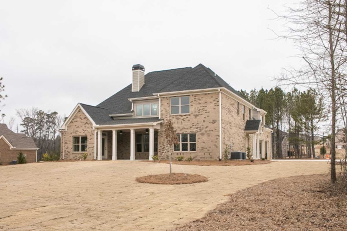 House plan exterior with brick facade, two stories, covered porch with columns, and prominent chimney.