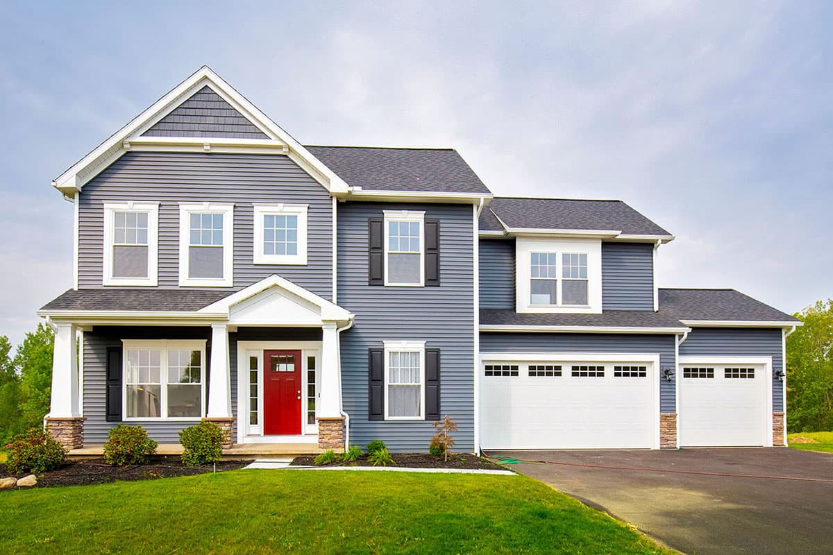 Two-story house plan exterior featuring a front porch with columns, a gabled roof, and a two-car garage with a matching roofline.