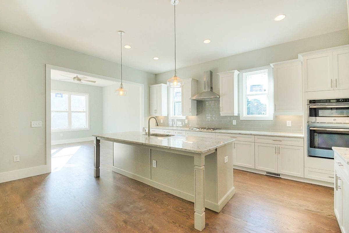 Kitchen with island, granite countertops, white cabinets, stainless steel appliances, and subway tile backsplash.