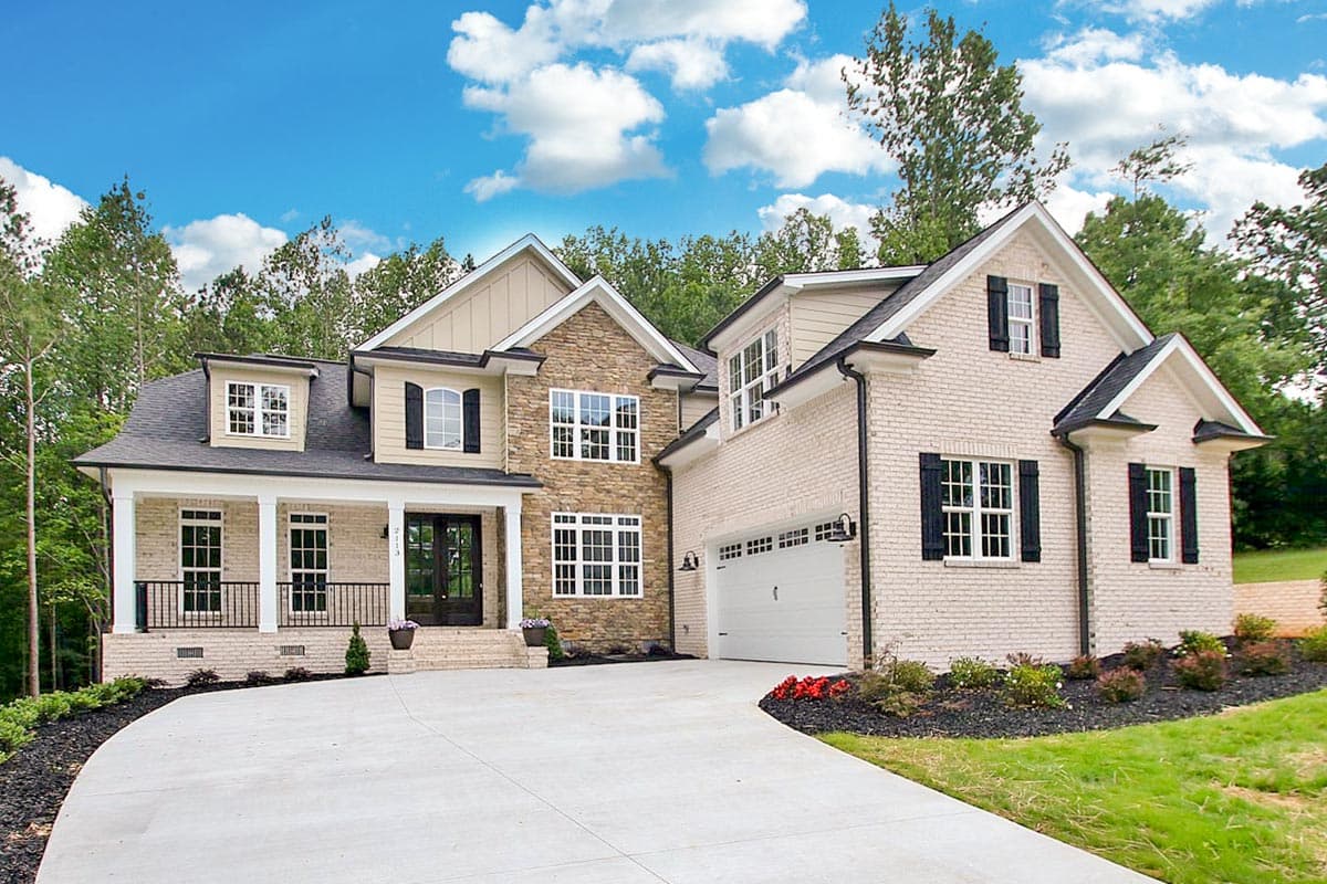 House plan exterior. Two-story home with a porch, gables, and a stone facade. Includes a side-entry garage and dormers.
