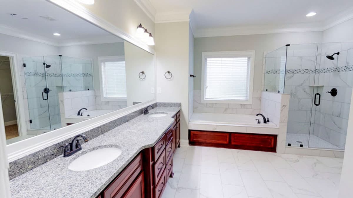 Spacious bathroom with double vanity, soaking tub, and glass-enclosed shower with marble tile.