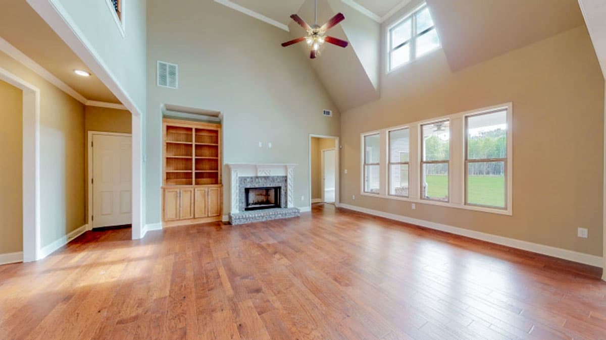 Great room with vaulted ceiling, fireplace, built-in bookshelves, and multiple large windows.
