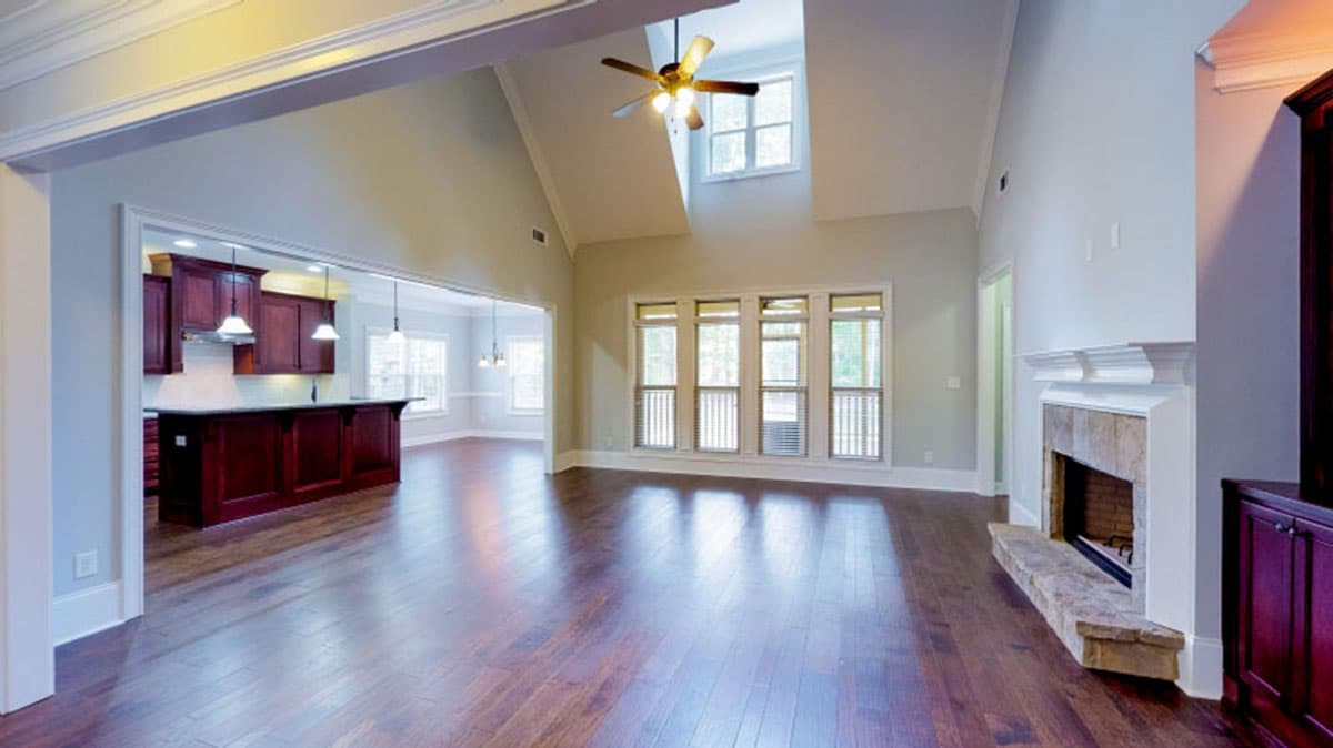 Great room with vaulted ceiling, fireplace, and open view to kitchen with island and dark wood cabinets.