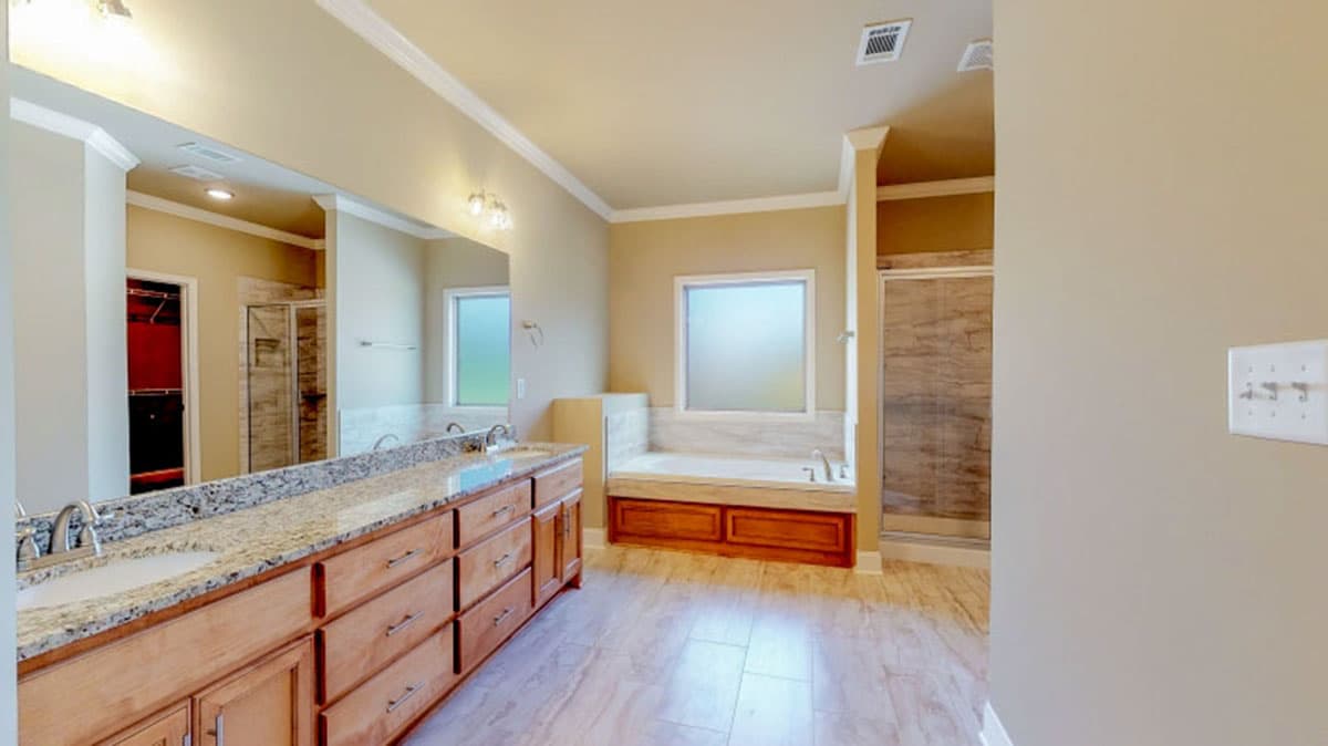 Spacious bathroom with double vanity, granite counters, built-in tub, walk-in shower, and closet.
