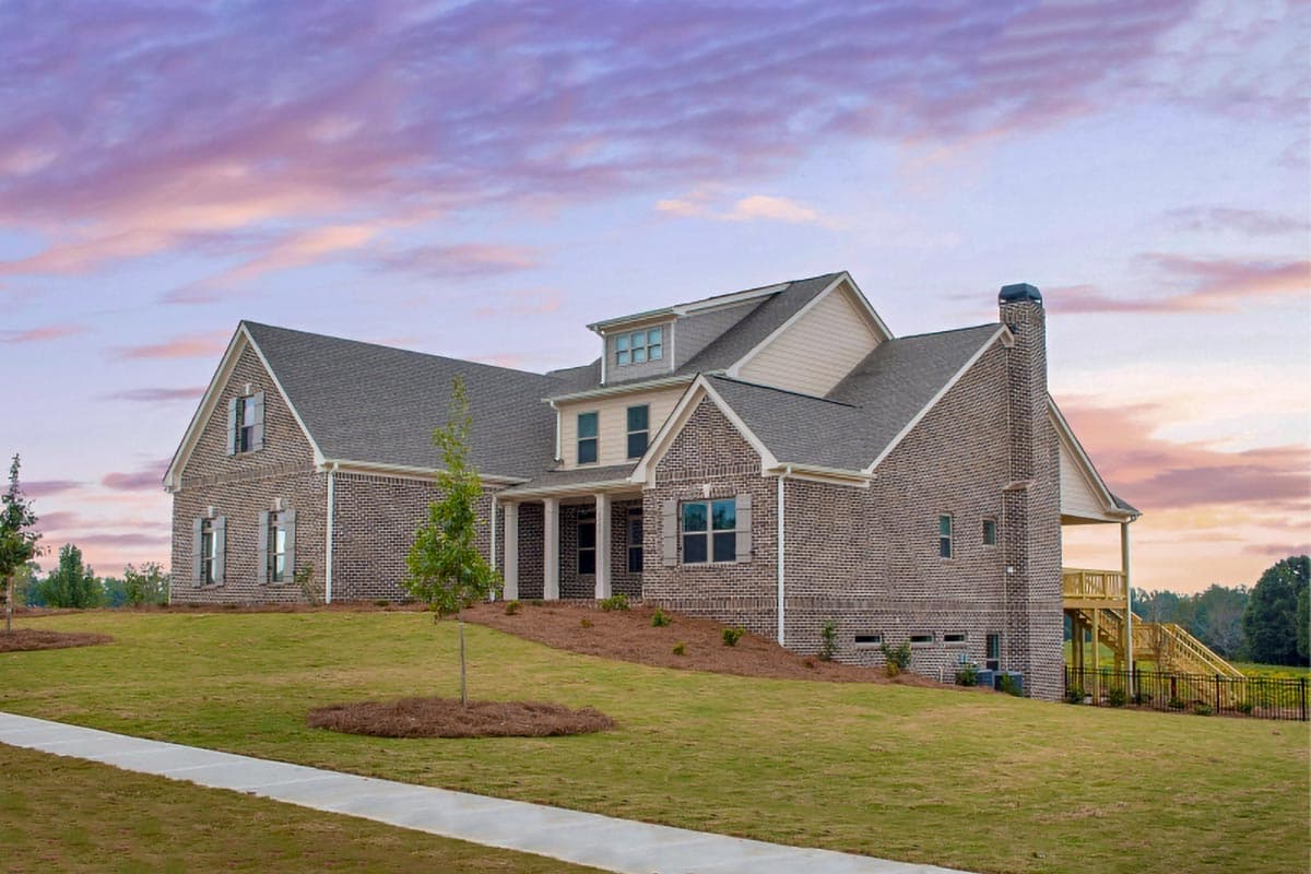 House plan exterior. Two-story brick home with gables, a covered porch, dormers, and a chimney.