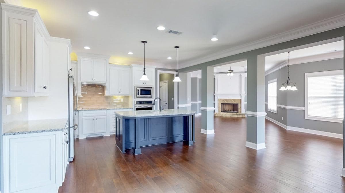 Open concept great room and kitchen with island, fireplace, and white cabinetry. Interior rendering.