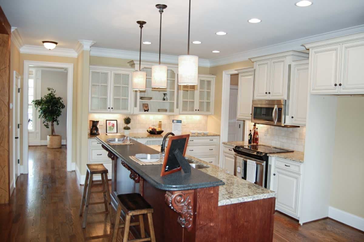 Kitchen with island, white cabinetry, granite countertops, stainless steel appliances, and pendant lighting.