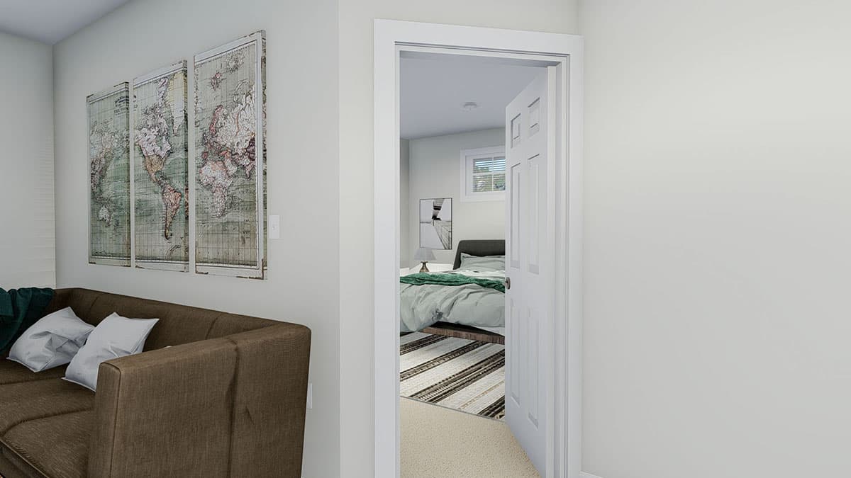Interior view of a bedroom with a queen bed and a window, seen through an open doorway from a living area with a sofa.