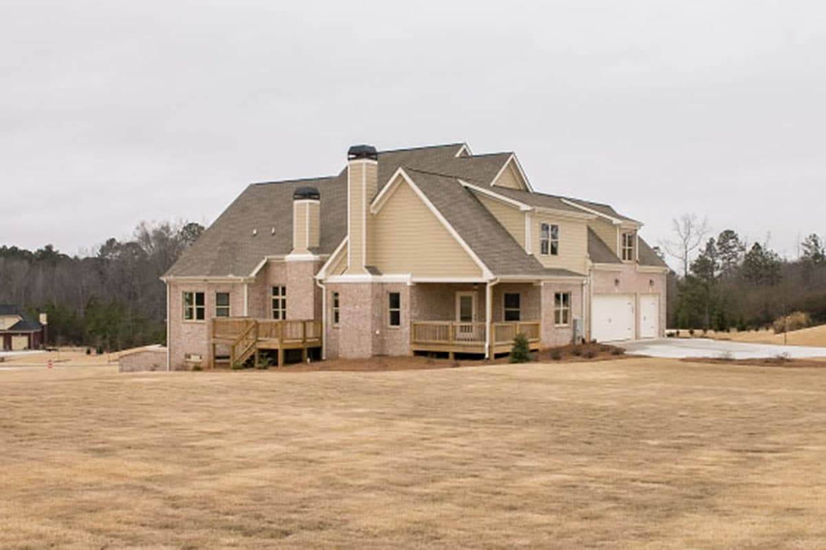 House plan exterior: Two-story home with brick accents, gabled dormers, multiple rooflines, and a three-car side-entry garage.