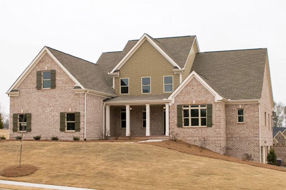 House plan exterior: Two-story brick home with covered porch, prominent gables, and varied rooflines.