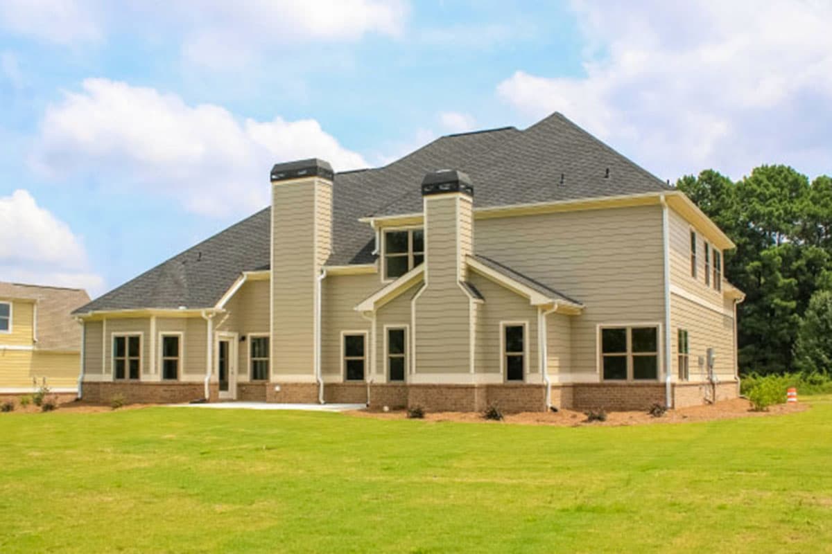 House plan exterior: two-story home with prominent chimneys, gabled dormers, and multiple windows.