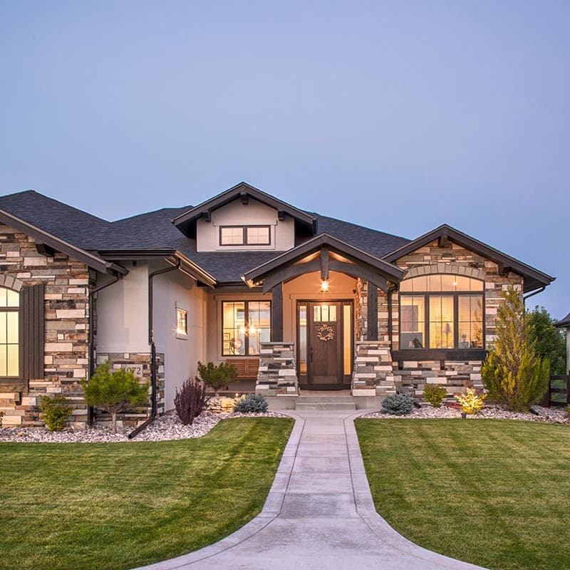 House plan exterior: single-story Modern Farmhouse with stone accents, prominent gabled entry, and wide eaves.