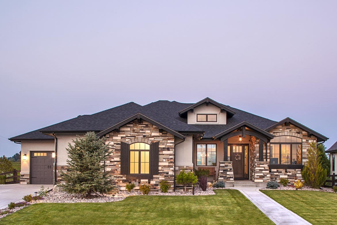 House plan exterior. Craftsman-style home with stone and stucco facade, arched windows, gables, and a covered front porch with dark timber columns.
