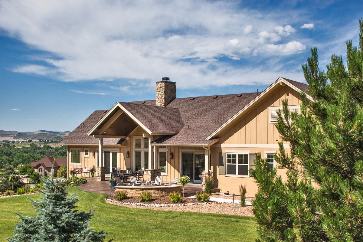 House plan exterior: Ranch style with covered patio, stone chimney, and large gables.