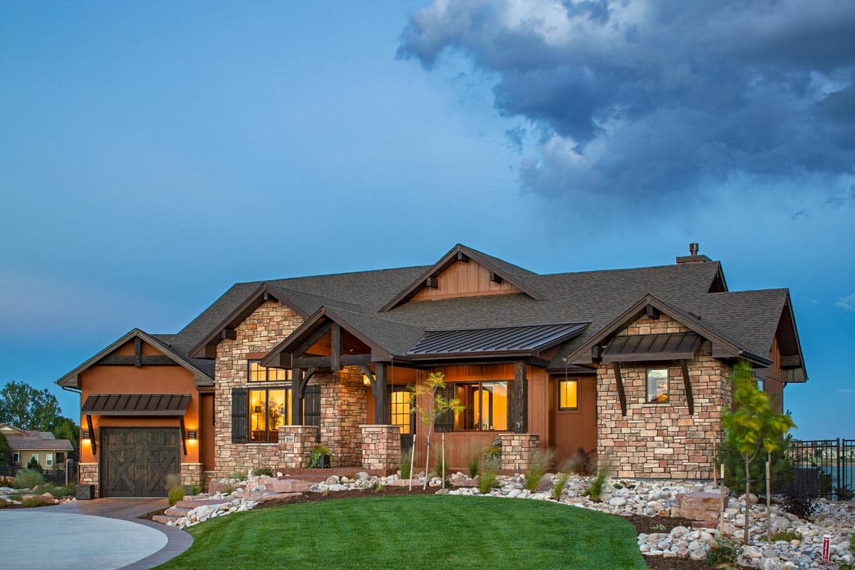 House plan exterior. Modern mountain style with stone and stucco facade, prominent gables, covered entry, and side-facing garage.