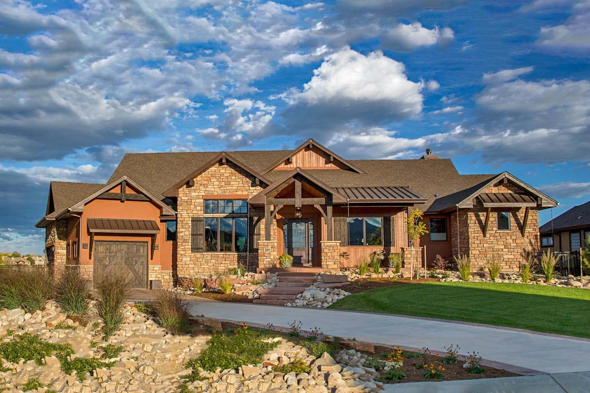 House plan exterior. Craftsman style with stone and wood accents. Features include a covered porch, gabled rooflines, and a front-entry garage.