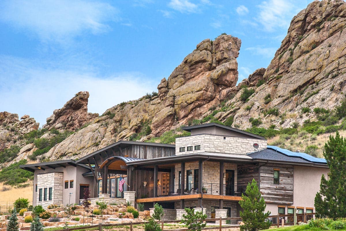 House plan exterior: Modern style with stone and wood facade, multiple gables, covered porch, and terraced landscaping.