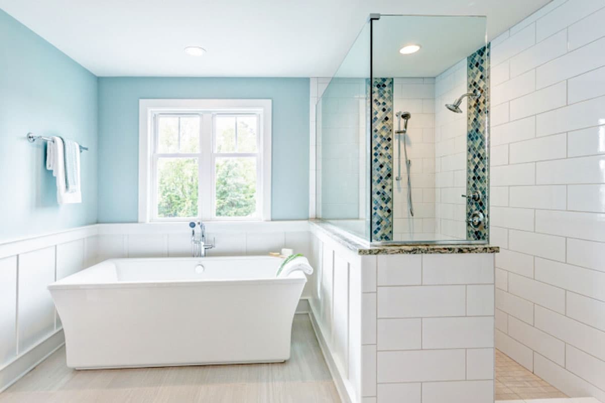 Bathroom with freestanding tub, glass-enclosed shower with mosaic tile accents, and white subway tile walls.