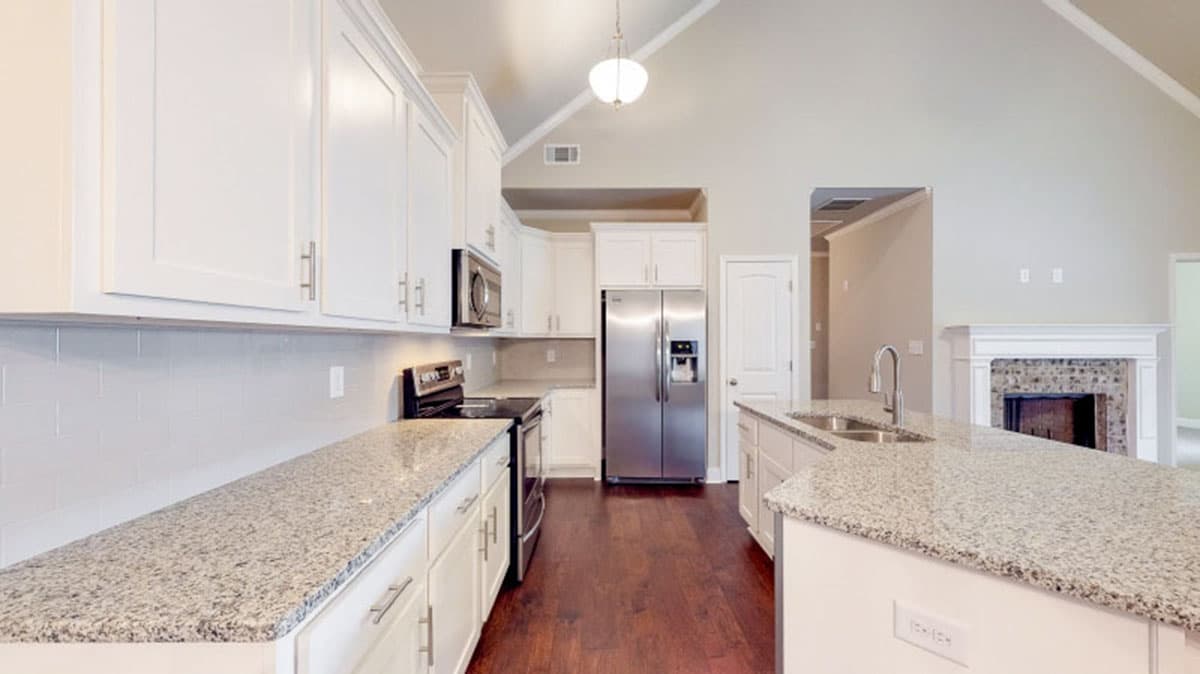 Kitchen with white cabinets, granite countertops, stainless steel appliances, island, and vaulted ceiling.