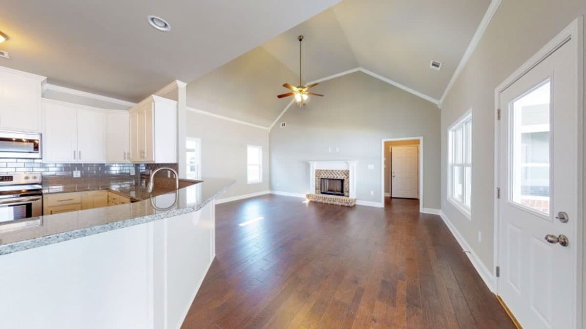 Open concept living space with vaulted ceiling, kitchen island, fireplace, and doors to exterior.