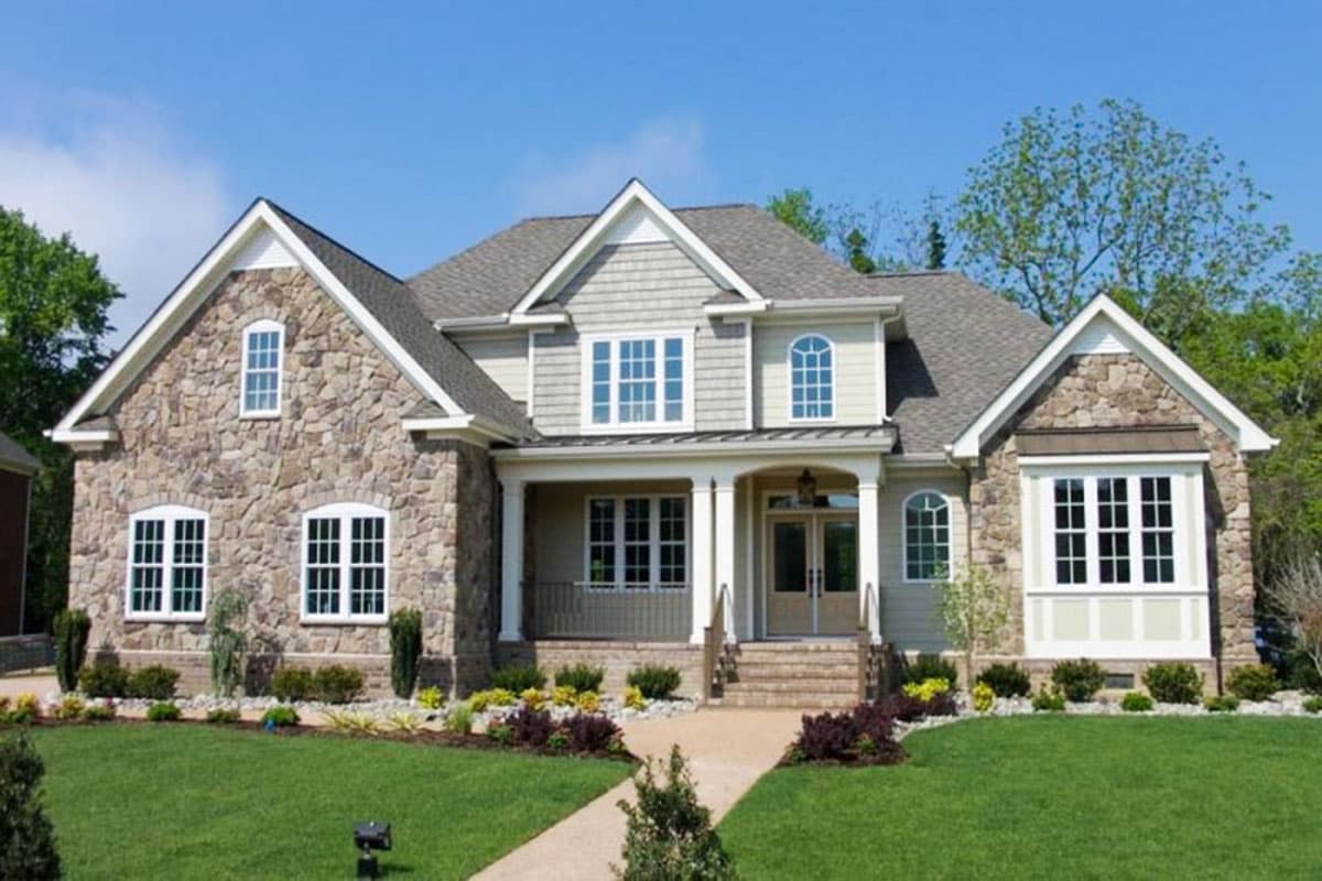 Two-story house plan exterior with stone facade, gables, dormers, and covered front porch with columns.
