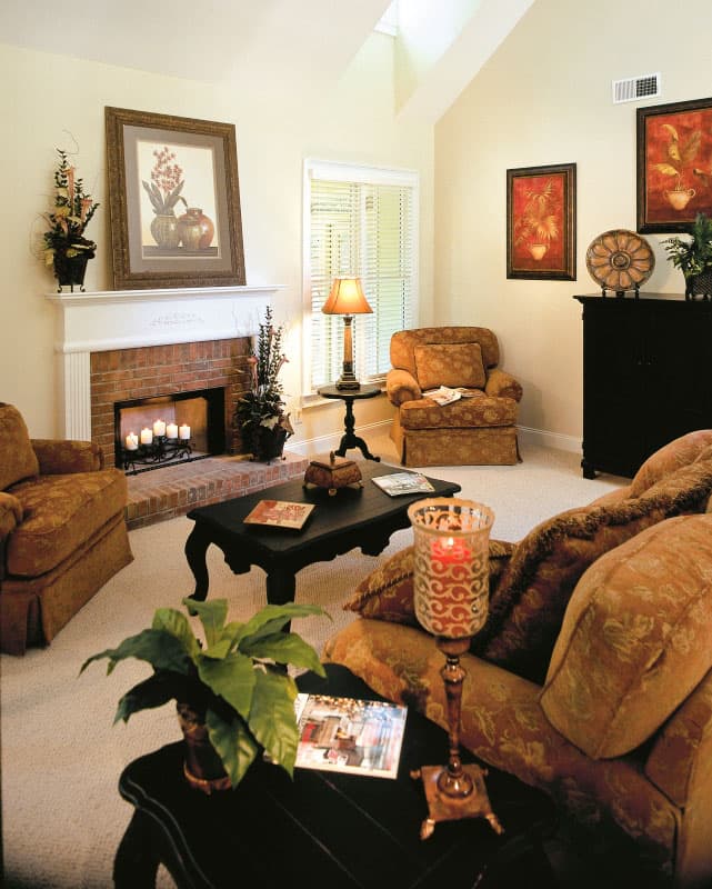 Living room with vaulted ceiling, brick fireplace, large windows, and a sectional sofa.