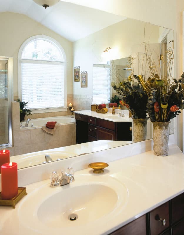 Bathroom with vaulted ceiling, arched window, dual vanities, and a soaking tub.