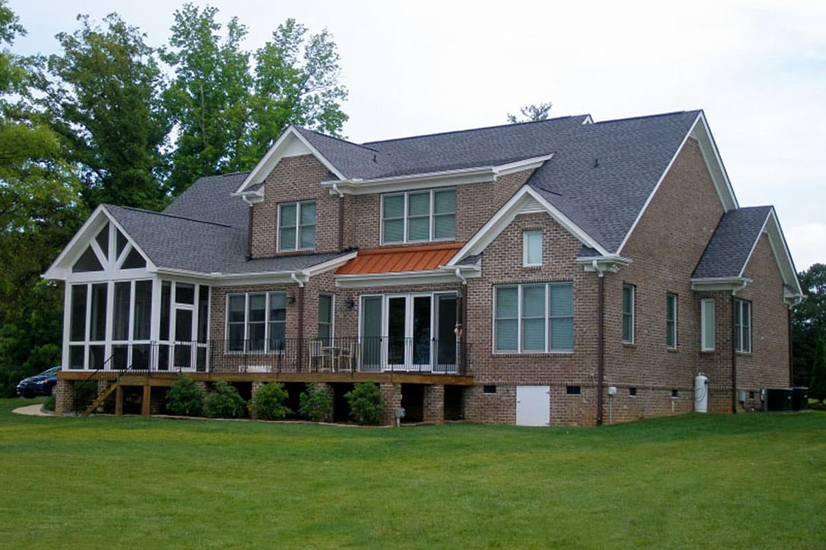 Two-story brick house plan exterior with a screened porch, gables, and copper metal roof over the rear entrance.